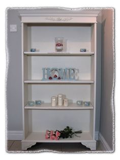 a white shelf with candles and flowers on it