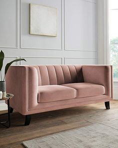 a living room with a pink couch and potted plant on the side table next to it