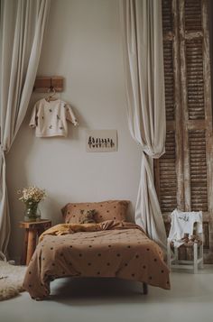 a bed sitting next to a window covered in curtains