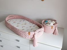 a baby crib with toys in it on top of a dresser next to a teddy bear