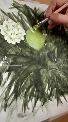 someone is painting flowers with green and white colors