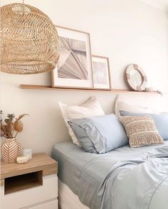 a bed with blue sheets and pillows on top of it next to a wooden shelf