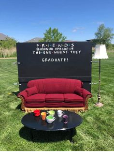 a red couch sitting in the grass next to a sign that says, fake friends are random things the one where they graduate