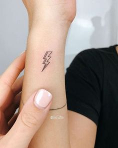 a woman's arm with a small lightning tattoo on the left side of her wrist