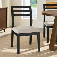 a dining room table with two chairs and a cabinet in front of the window on carpeted floor