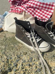 two pairs of black and white shoes sitting on the ground next to a pile of clothes