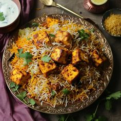 a plate filled with tofu and rice on top of a purple cloth next to bowls of yogurt