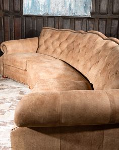 a couch and ottoman in a room with wood paneling on the wall behind it