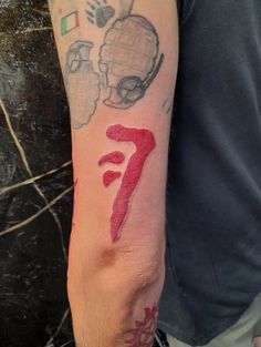 a man's arm with tattoos on it and the number seven painted on it