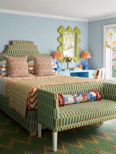 a bedroom with blue walls and green carpeted flooring is decorated in bold patterns