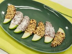 a green plate topped with apple slices covered in granola and powdered sugar on top of it