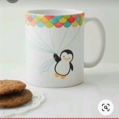 a cookie is next to a coffee mug with a penguin on it