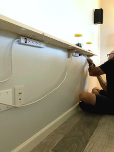 a man sitting on the floor working on an electrical outlet with wires attached to it