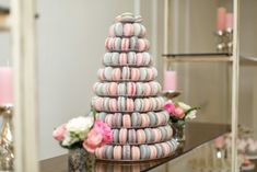 a stack of macaroons sitting on top of a table next to candles and flowers