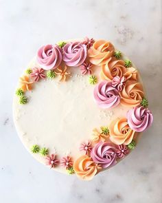 a cake decorated with pink and orange icing on a white counter top next to a knife