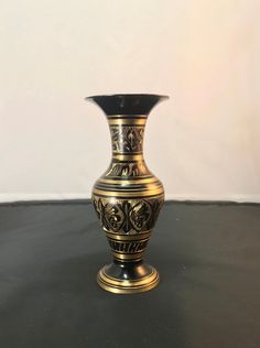 a black and gold vase sitting on top of a table