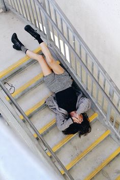 a woman laying on top of a set of stairs with her legs up and feet down