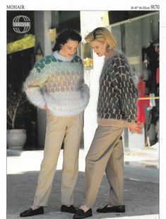 two women standing next to each other in front of a building wearing sweaters and slacks