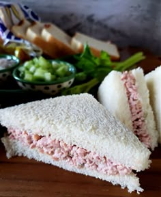 a sandwich cut in half sitting on top of a wooden cutting board next to salad