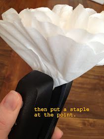 a hand holding a white tissue paper over a black object with the words then put a staple at the point