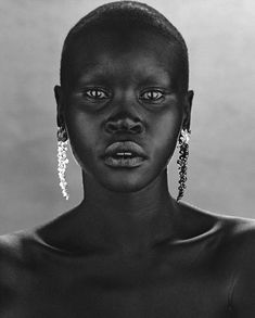 an african woman with large earrings on her head and dark skin, looking at the camera