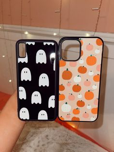 two cell phones with halloween themed cases on them, one is black and the other is orange