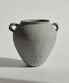 a large gray vase sitting on top of a white table next to a black and white wall