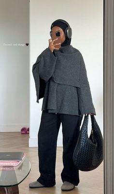 a person with headphones and a handbag standing in front of a glass table