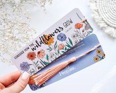 someone holding up a business card with flowers on it and the words wildflowers grow