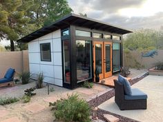 a backyard with a couch, chair and small shed in the middle of it's back yard