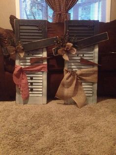 two old shutters decorated with burlocks and bows are sitting in front of a window