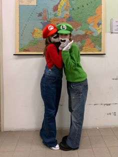 two people standing next to each other in front of a wall with a map on it