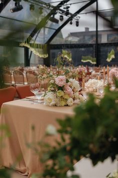 the table is set up with flowers and wine glasses for an elegant wedding reception in a greenhouse