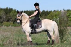 a woman riding on the back of a white horse in a field with tall grass