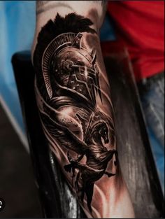 a man's arm with a black and grey tattoo on it