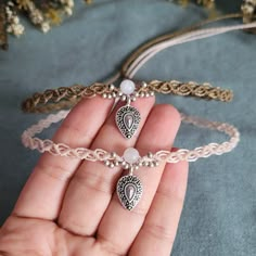 a hand holding three different bracelets with charms on each strand and one bead