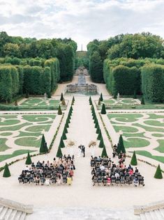 an outdoor wedding ceremony in the middle of a formal garden