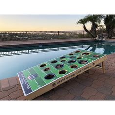 a table that is next to a pool with a football field on it and holes in the middle