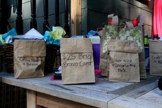 several bags with wine bottles on them sitting on a wooden table in front of a building