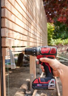 a person holding a drill and an electric screwdriver in front of a house