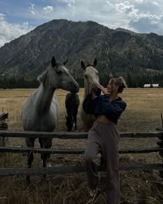 a woman standing in front of two horses