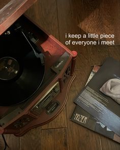 a record player sitting on top of a wooden floor next to a pile of records