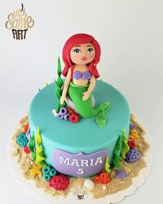 a cake with a little mermaid sitting on top of it