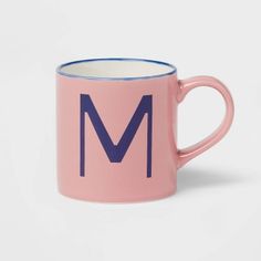 a pink and blue coffee mug with the letter m on it's bottom half