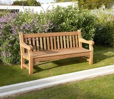 a wooden bench sitting in the middle of a lush green field next to a bird feeder