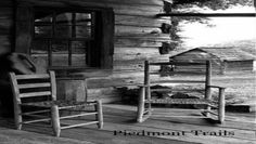 two rocking chairs sitting on the porch of a log cabin in front of a window