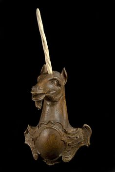 a wooden horse head with a long horn on it's head and two horns sticking out of its mouth