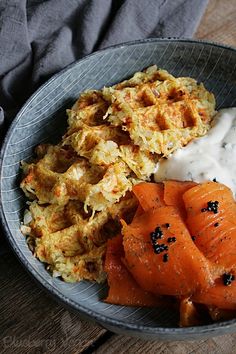 a bowl filled with carrots, mashed potatoes and sour cream on top of a wooden table