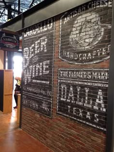 a brick wall with signs on it in the middle of a room filled with people