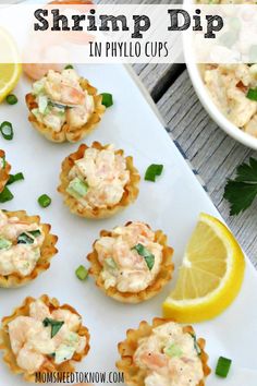 small appetizers are arranged on a plate with lemon wedges and garnishes